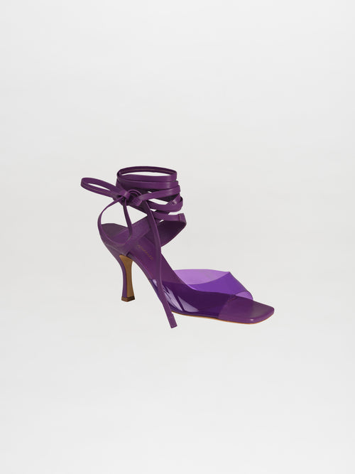 The Marlene Heels Purple is a single high-heeled sandal made from luxurious Italian calf leather, showcasing elegant ankle straps against a plain white background.