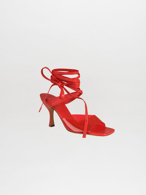 Marlene Heels in red, showcasing an eye-catching ankle wrap adorned with PVC transparent straps against a white backdrop.