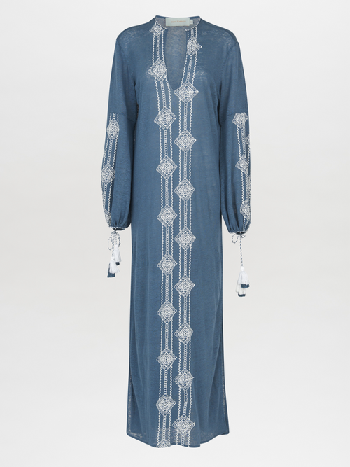 A navy blue, long-sleeved Mayfair Tunic Navy Embroidered with a V-neckline featuring white geometric embroidery down the front and on the sleeves, finished with tasseled ties at the cuffs.