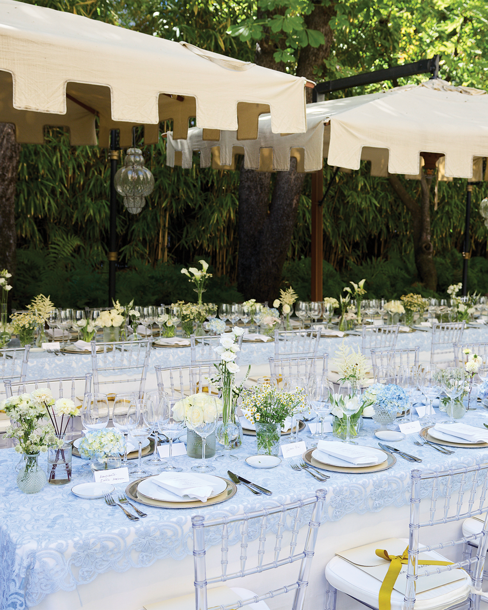 Outdoor wedding reception with tables set for dinner, white tablecloths, and floral centerpieces.
