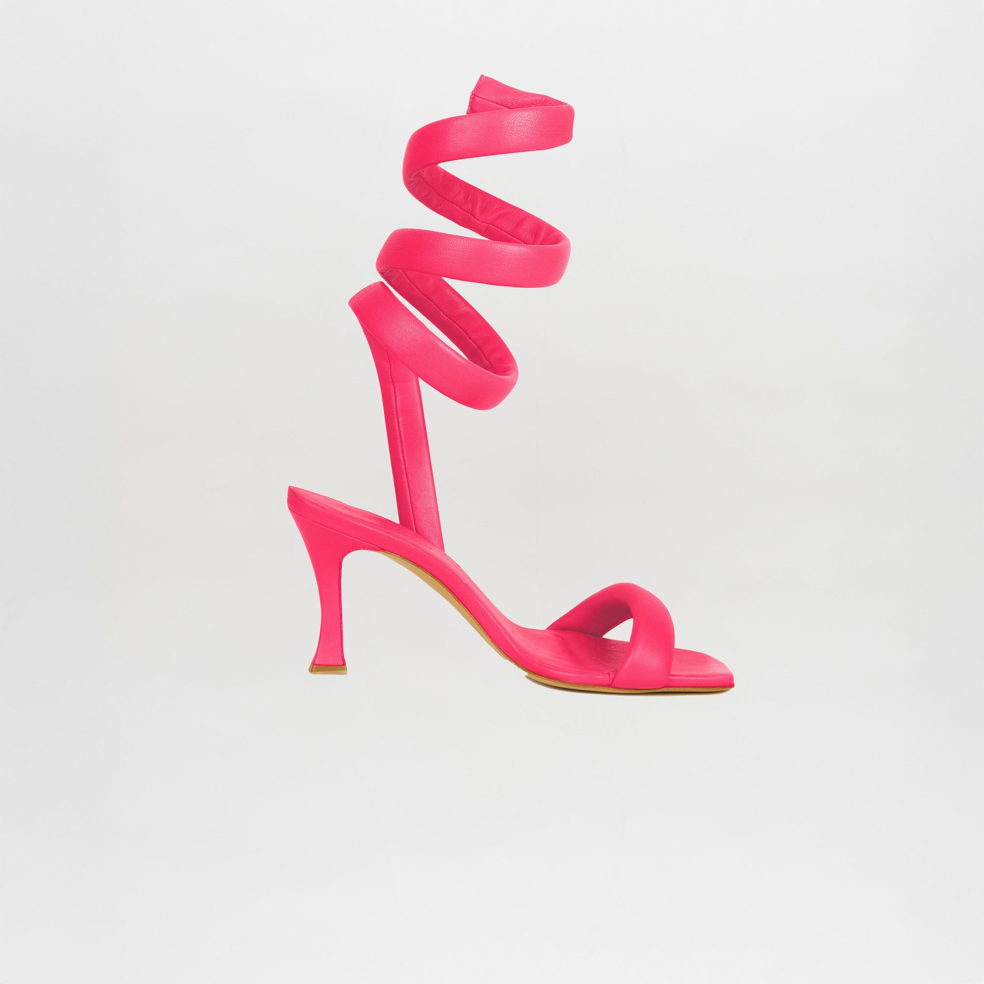 The Mika Heels Orchid are vibrant pink sandals made from Italian calf leather, featuring a spiral ankle strap and set against a clean white background.