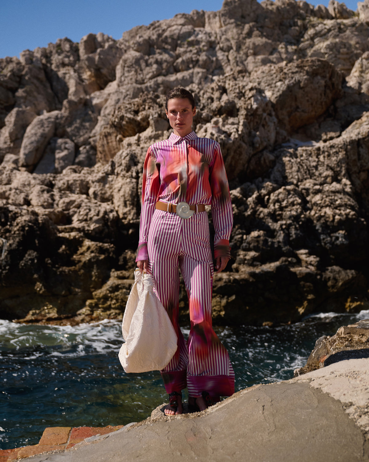 Person in a colorful outfit standing by rocky waters