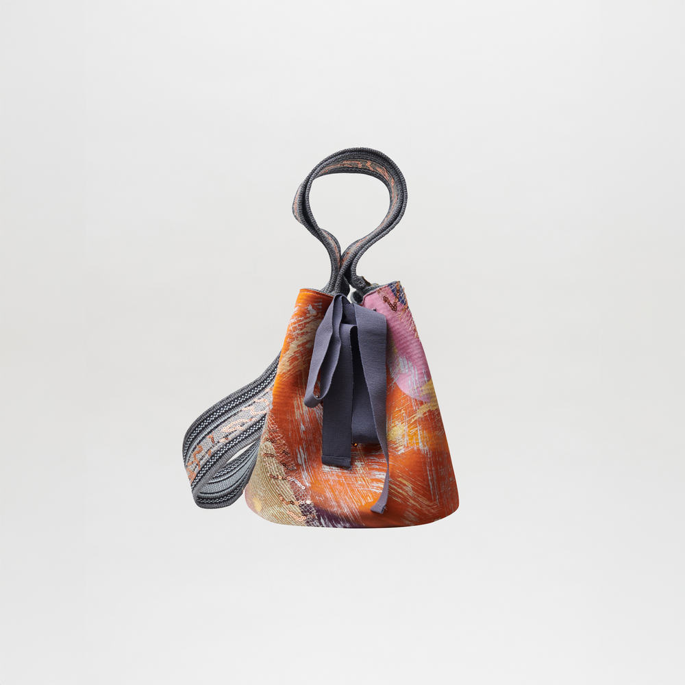 Mochila Laaput Gray with a textured, multicolored design, featuring a looped handle and fabric ribbons—a unique piece showcasing traditional craftsmanship.