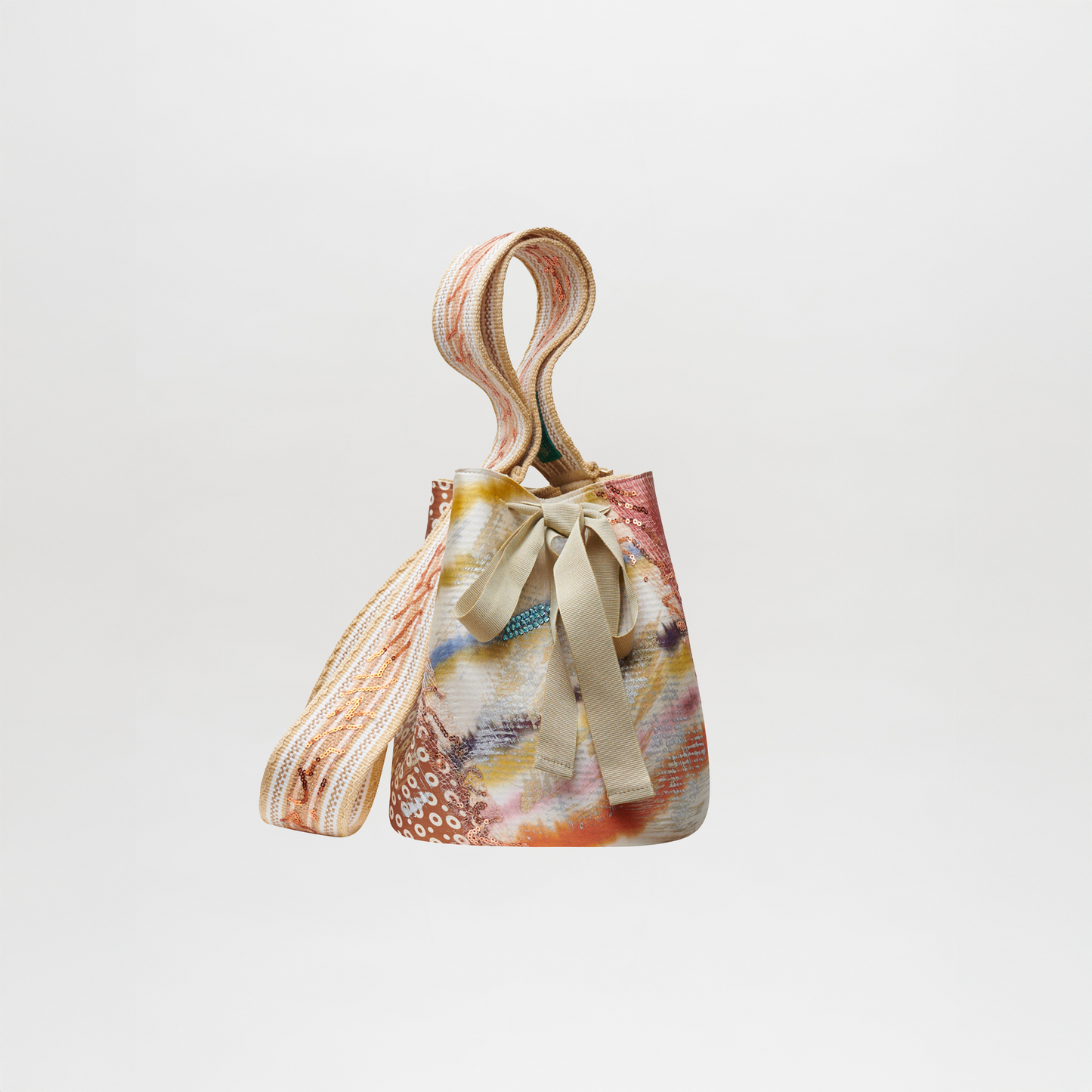 Colorful patterned Mochila Laaput Pearl handbag with a bow and braided strap against a white background.