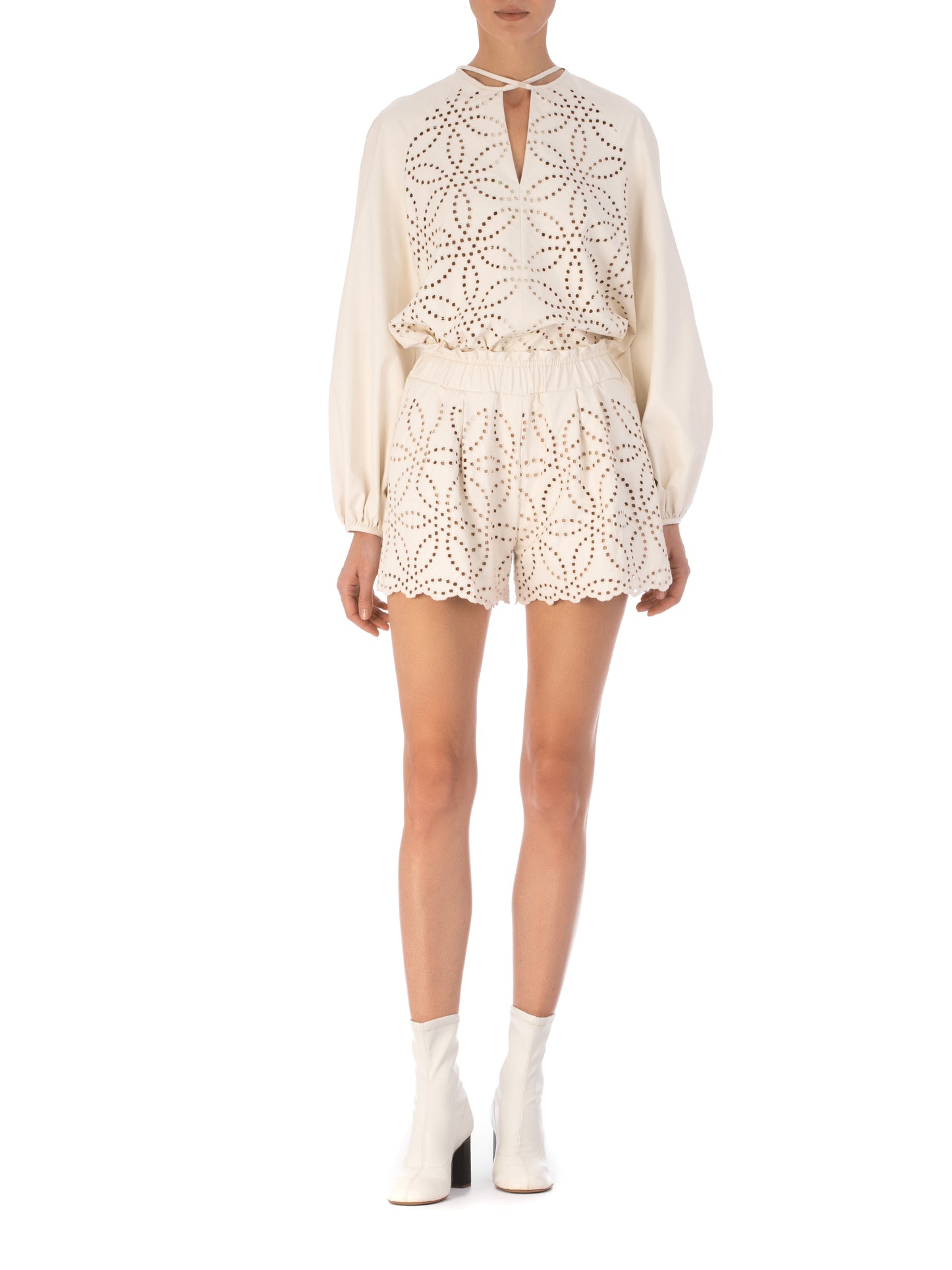 The Molveno Blouse Pearl is a white long-sleeve ecoleather blouse, featuring a geometric pattern on the front, a keyhole neckline, and a rounded hem.