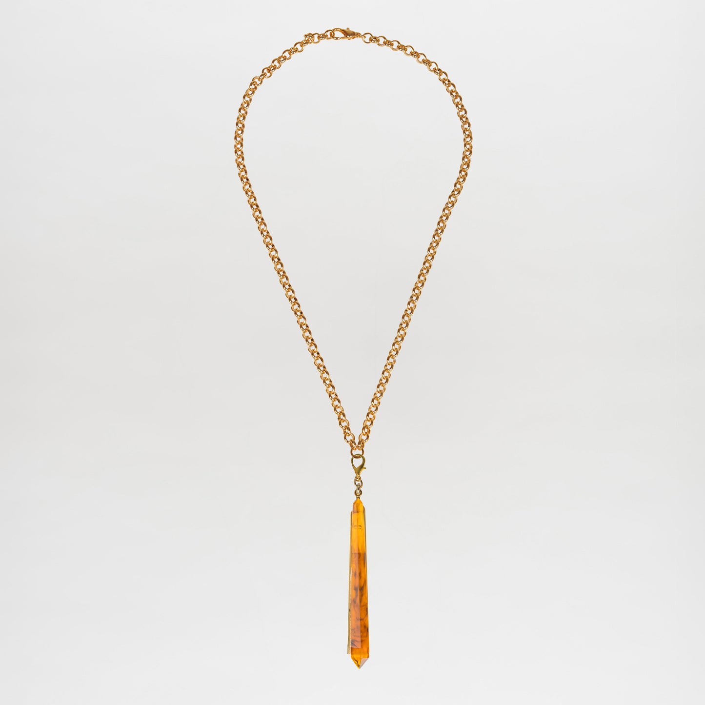 The Montse Necklace is a gold chain layering piece featuring a geometric amber crystal pendant, elegantly centered and crafted in Italy, shown against a plain white background.