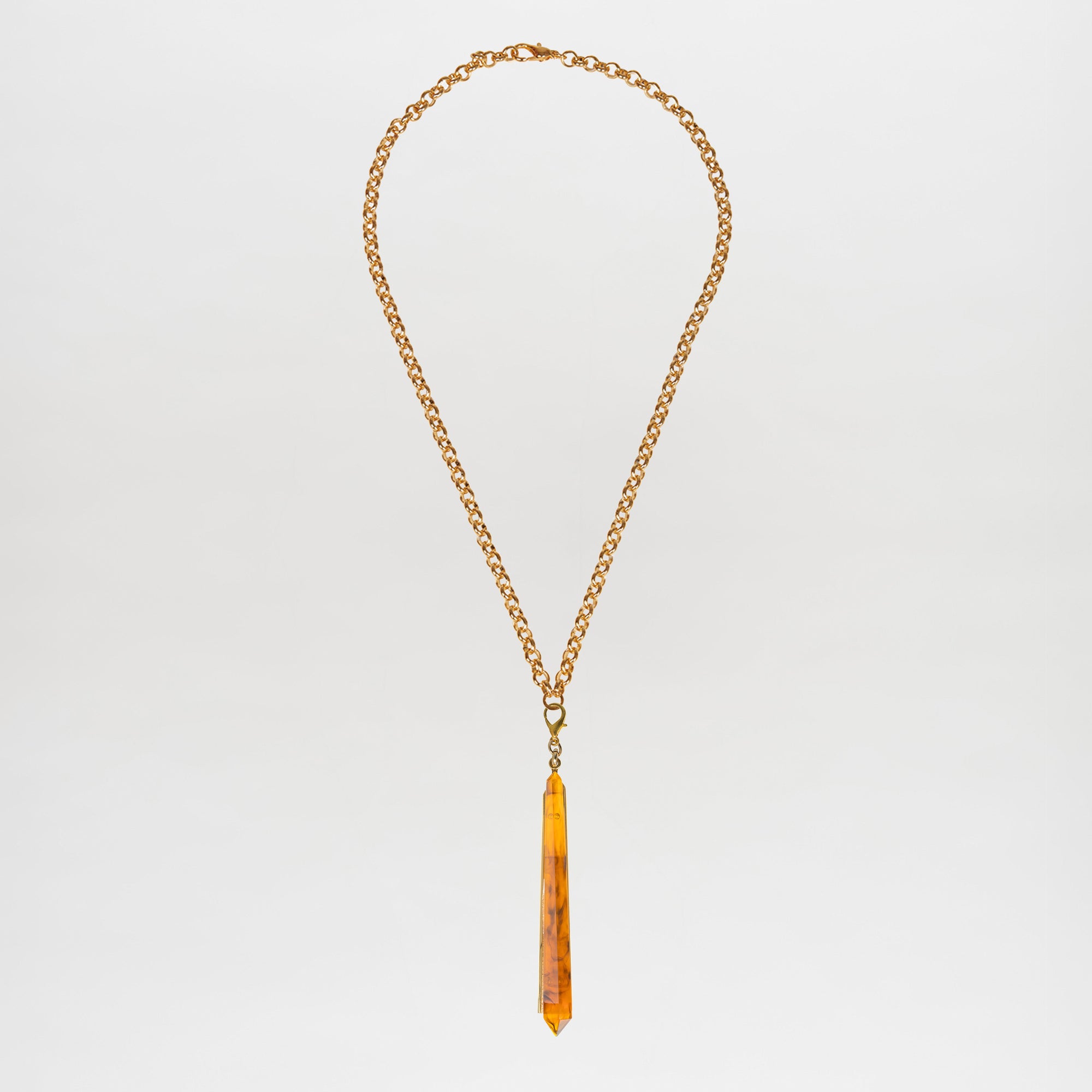 The Montse Necklace is a gold chain layering piece featuring a geometric amber crystal pendant, elegantly centered and crafted in Italy, shown against a plain white background.