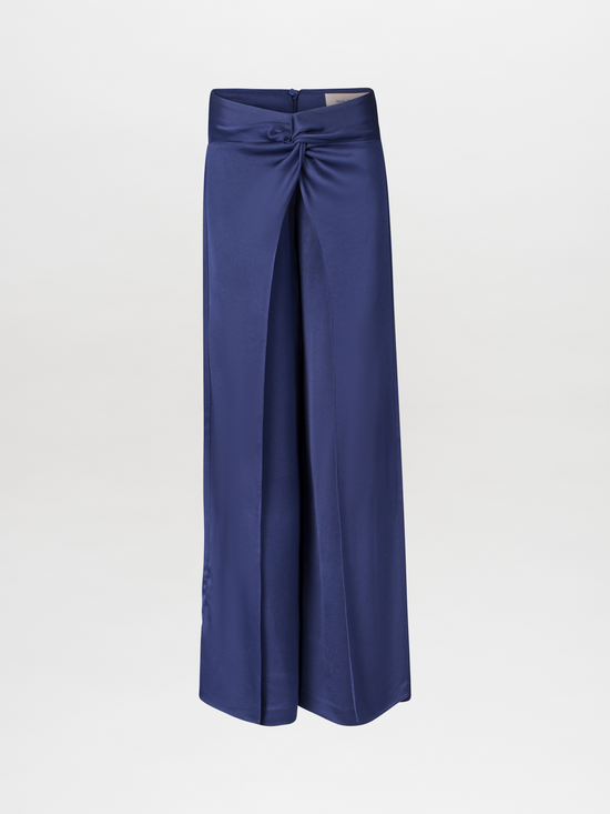 The Nadira Pant Navy is a pair of wide-leg pants made from hammered silk, featuring a high-waisted silhouette with a knot detail at the front.