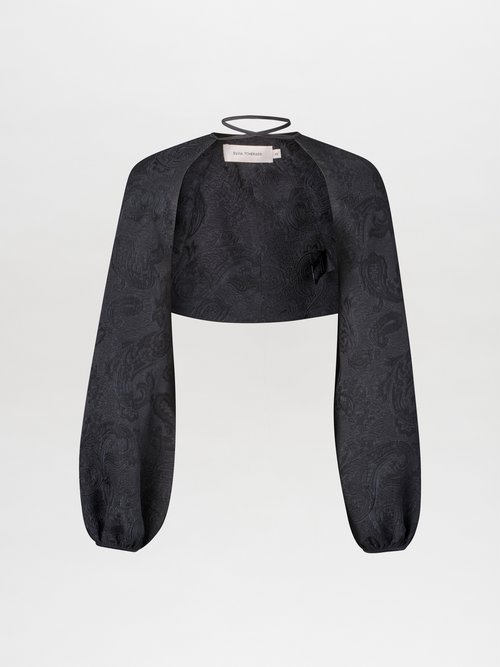 The Nana Cape Black is a black crop top with long puff sleeves and a subtle paisley pattern, crafted from viscose jacquard fabric against a plain white background.