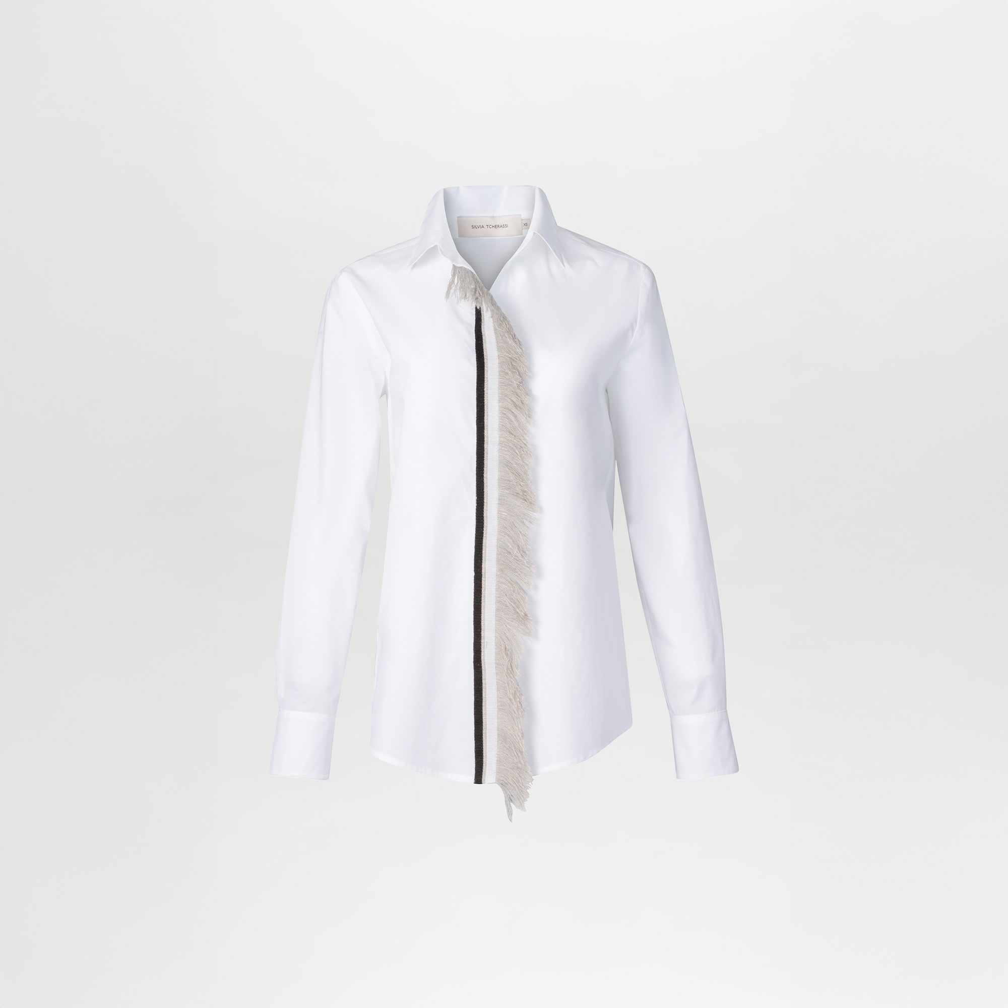The Naroa Blouse is a white long-sleeve button-up shirt featuring a traditional collar and an asymmetrical lace fringe detail on the front.