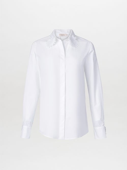 Naroa Blouse White features a long-sleeve cotton design with floral embroidery on the classic shirt collar, set against a plain white backdrop.