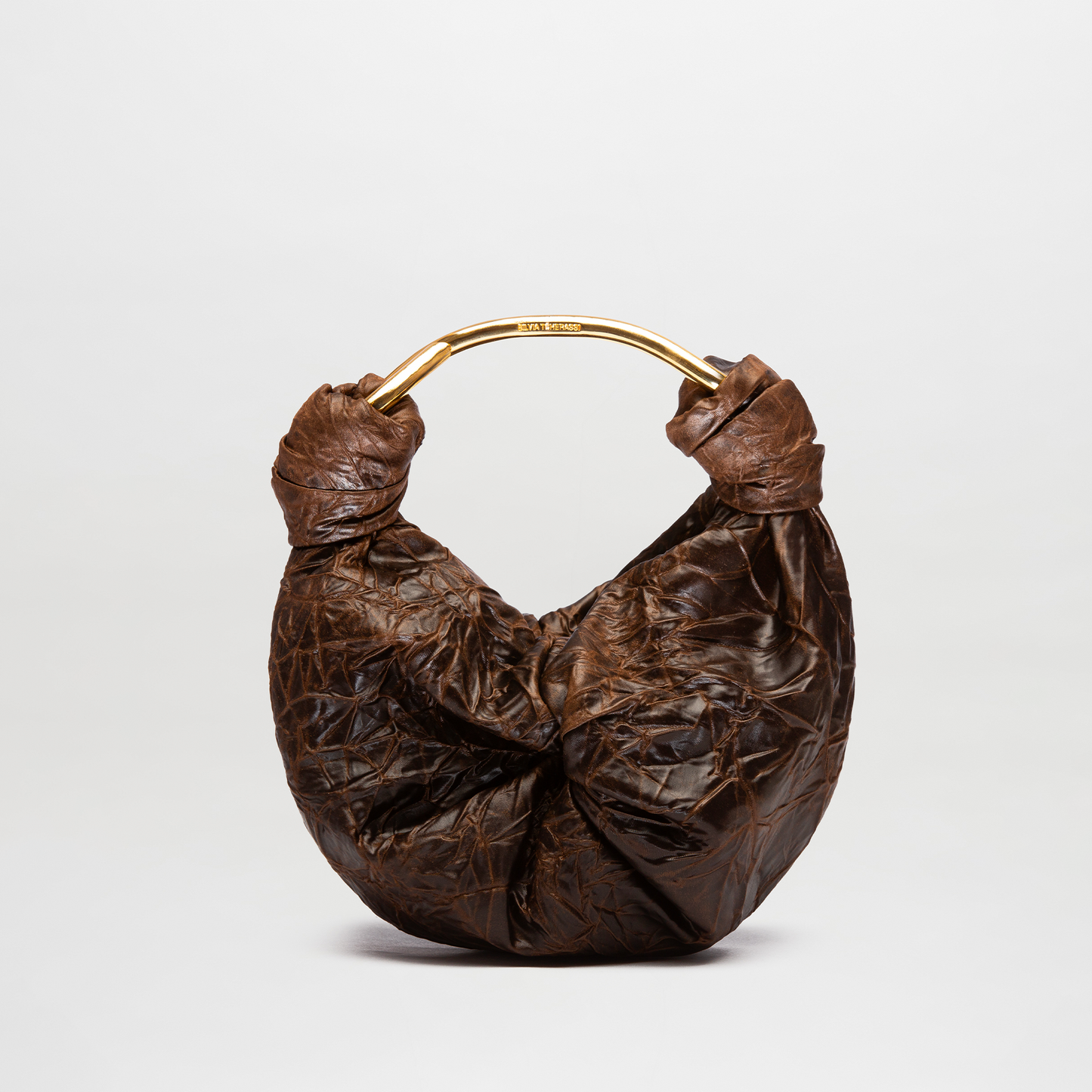 Brown leather handbag with gold handle on a light gray background