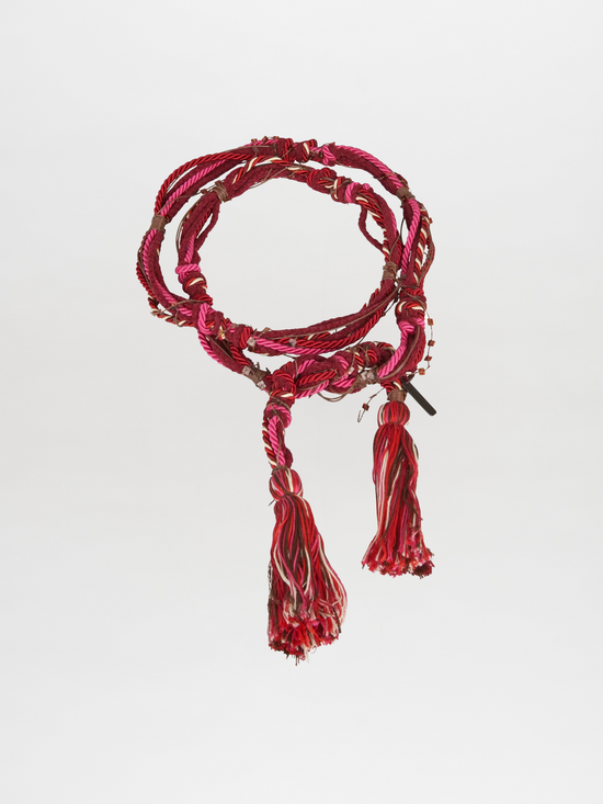 Introducing the Nellie Belt Fuchsia, a stunning twisted red and pink braided accessory with tassels at the ends, highlighting a vibrant fuchsia hue against a plain background. An ideal addition to your Pre Fall 2023 collection.