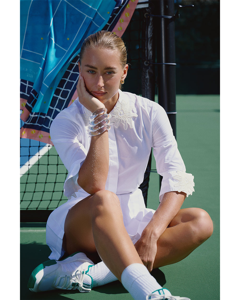 Woman in a white outfit sitting on a tennis court