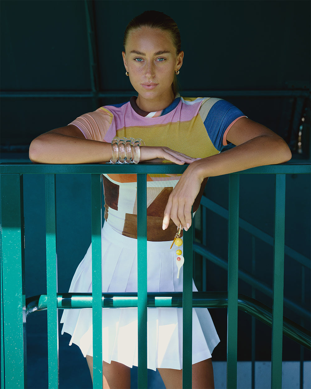 Woman in a colorful outfit leaning against a green railing.
