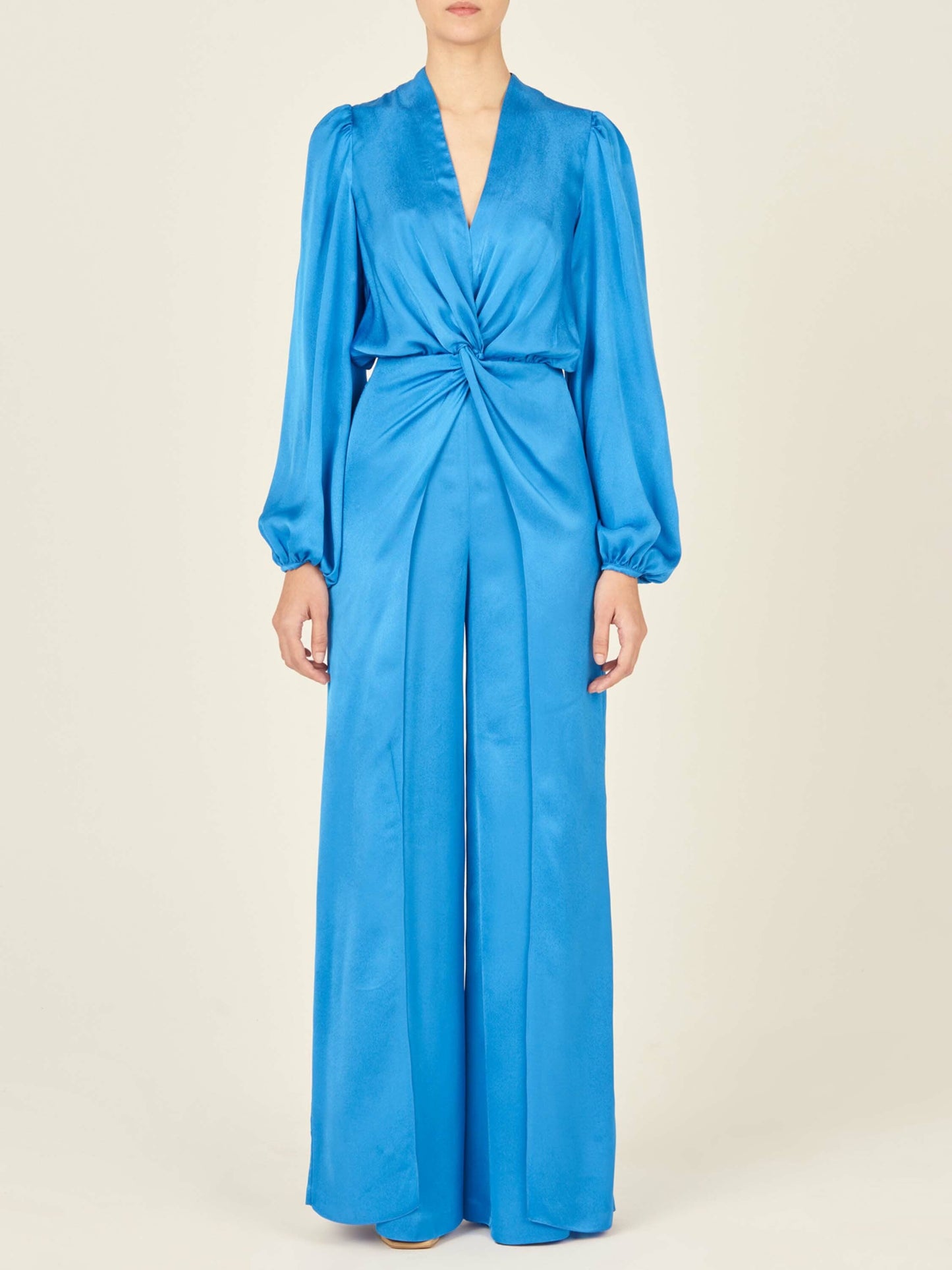 Woman standing with her back facing the camera, wearing the Arnetia Jumpsuit Blue with wide-leg pants.