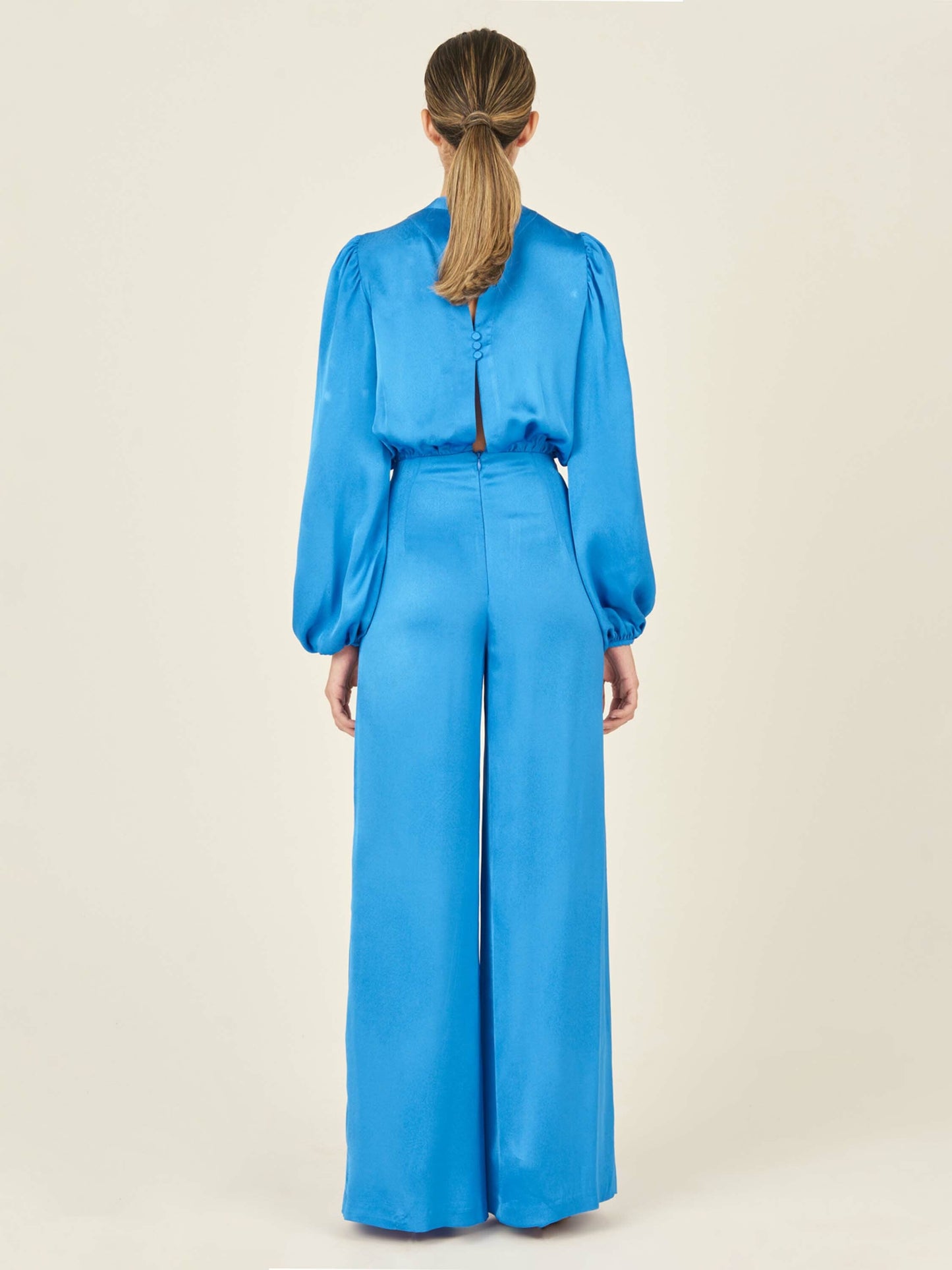 Arnetia Jumpsuit Blue with long sleeves, a keyhole neckline, and wide-leg pants, isolated on a white background.