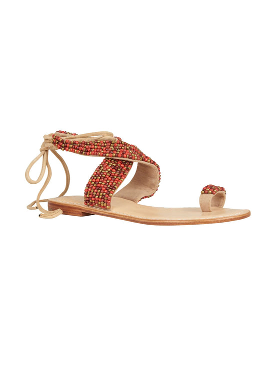 The Turin Sandal Red features a single flat design with a tan sole and red beaded straps, complete with an ankle wrap tie design. It will ship within two weeks of placing your order.