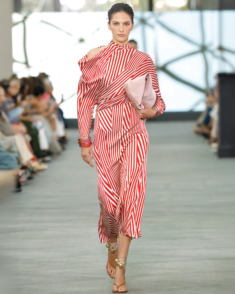 Model walking on a runway wearing a red and white striped outfit.