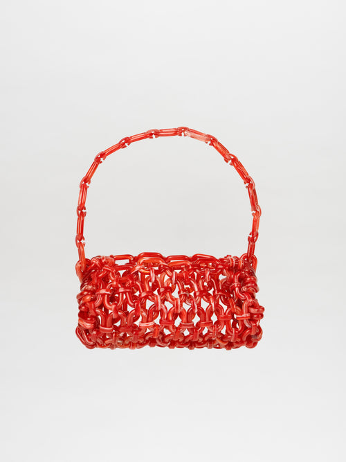 A red Piceno Handbag, featuring a woven design and a matching handle, shaped like a baguette-like rectangle, is displayed against a plain white background.