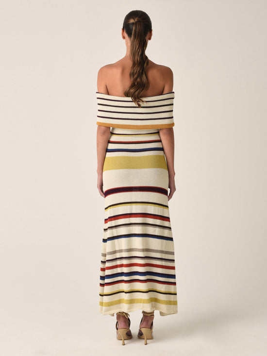 Introducing the Eva Dress Multi Mustard Stripe: a sleeveless, off-the-shoulder marvel crafted from 100% baby alpaca. This form-fitting top flares out slightly at the bottom and features vibrant, multi-colored stripes including yellow, brown, red, and blue.