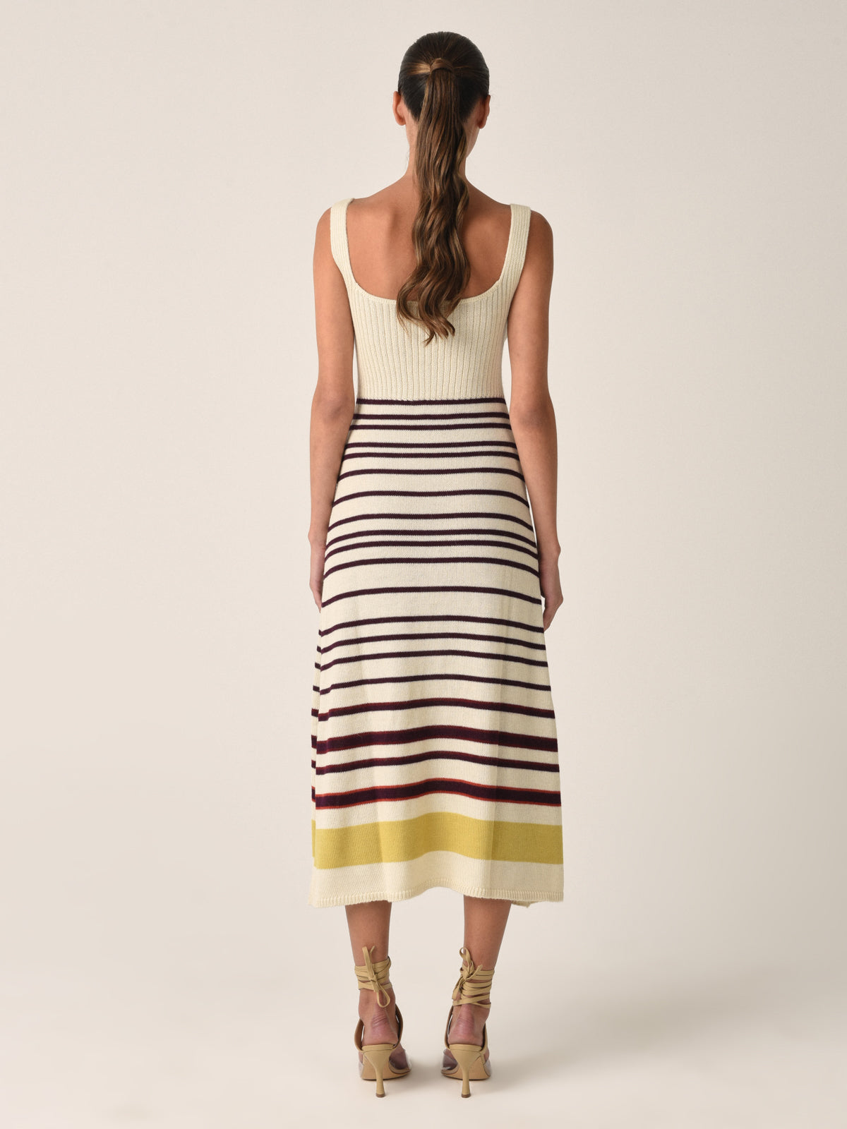 Sleeveless a-line Muriel Dress Multi Mustard Stripe with a beige top and horizontal stripes in black, red, and yellow on the skirt, displayed on a white background.