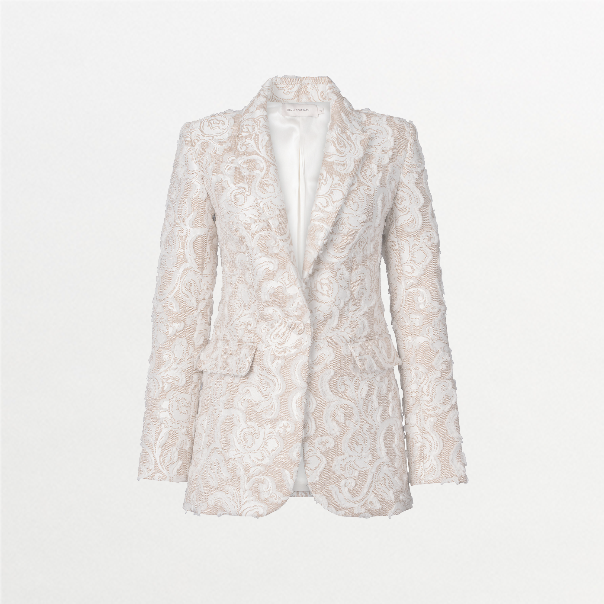 A person with slicked-back hair wears the Rebeca Jacket in Abstract White Floral and matching pants, looking to the side against a blue background. Mark your calendars for September 2nd, 2024; outfits like this will ship between August 19th and that date.