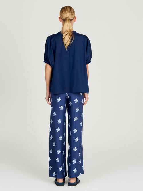 A woman's Emine Pant Navy Bloom with white floral patterns.