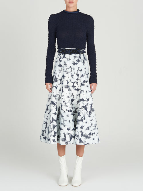 Sentence with product name: A Grettel Skirt White Denim with a black and white print, made of textured denim fabric.