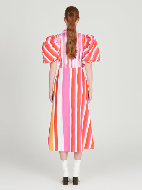 A Pavia Dress Rouge Orange Stripes with a brushstroke stripe print and a bow.