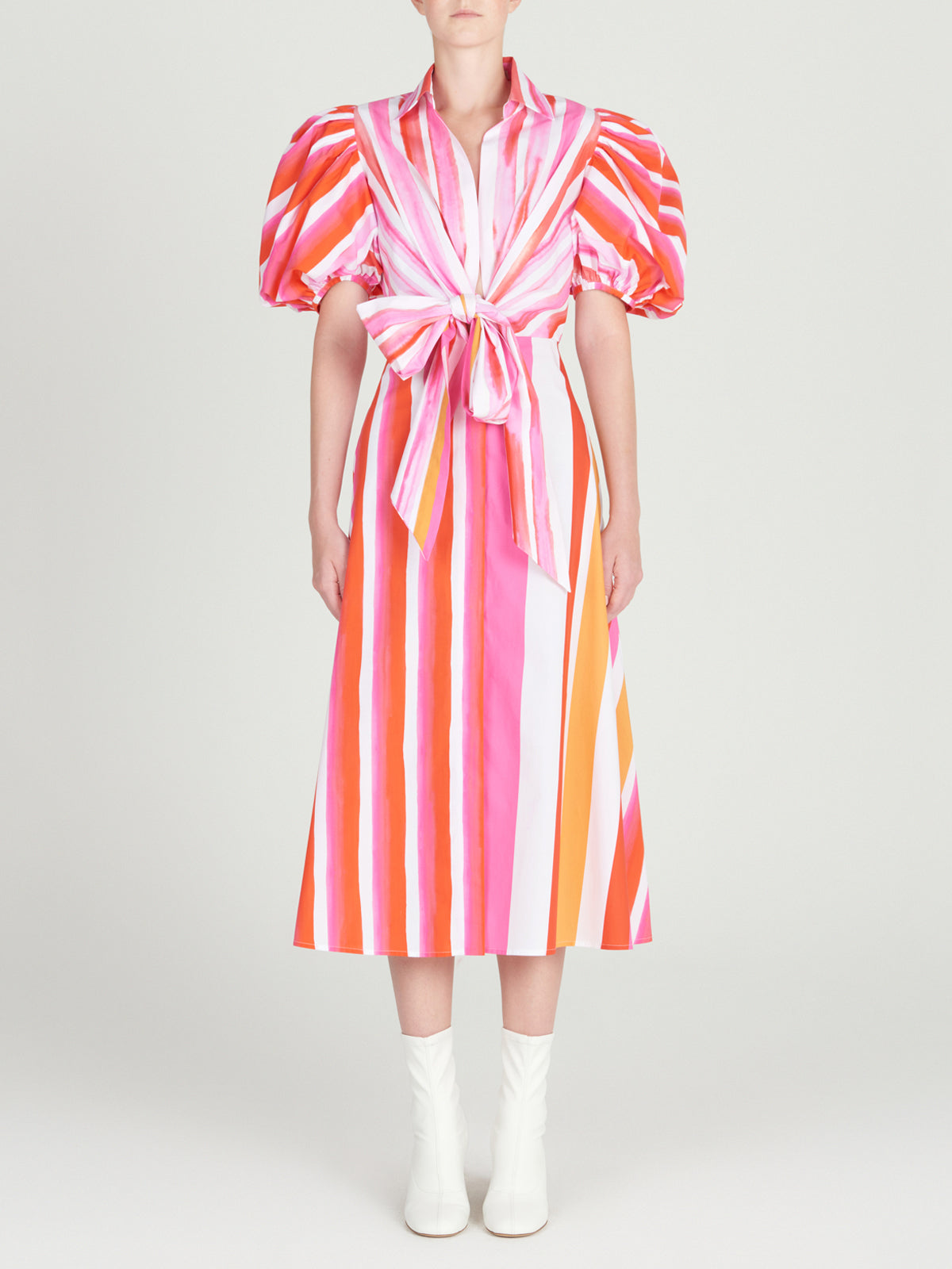 A Pavia Dress Rouge Orange Stripes with a brushstroke stripe print and a bow.