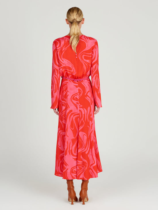 The Pesaro Dress Pink Red Marble is a long-sleeved transitional day-to-night piece, showcasing an abstract swirl pattern with a floral waistband detail.