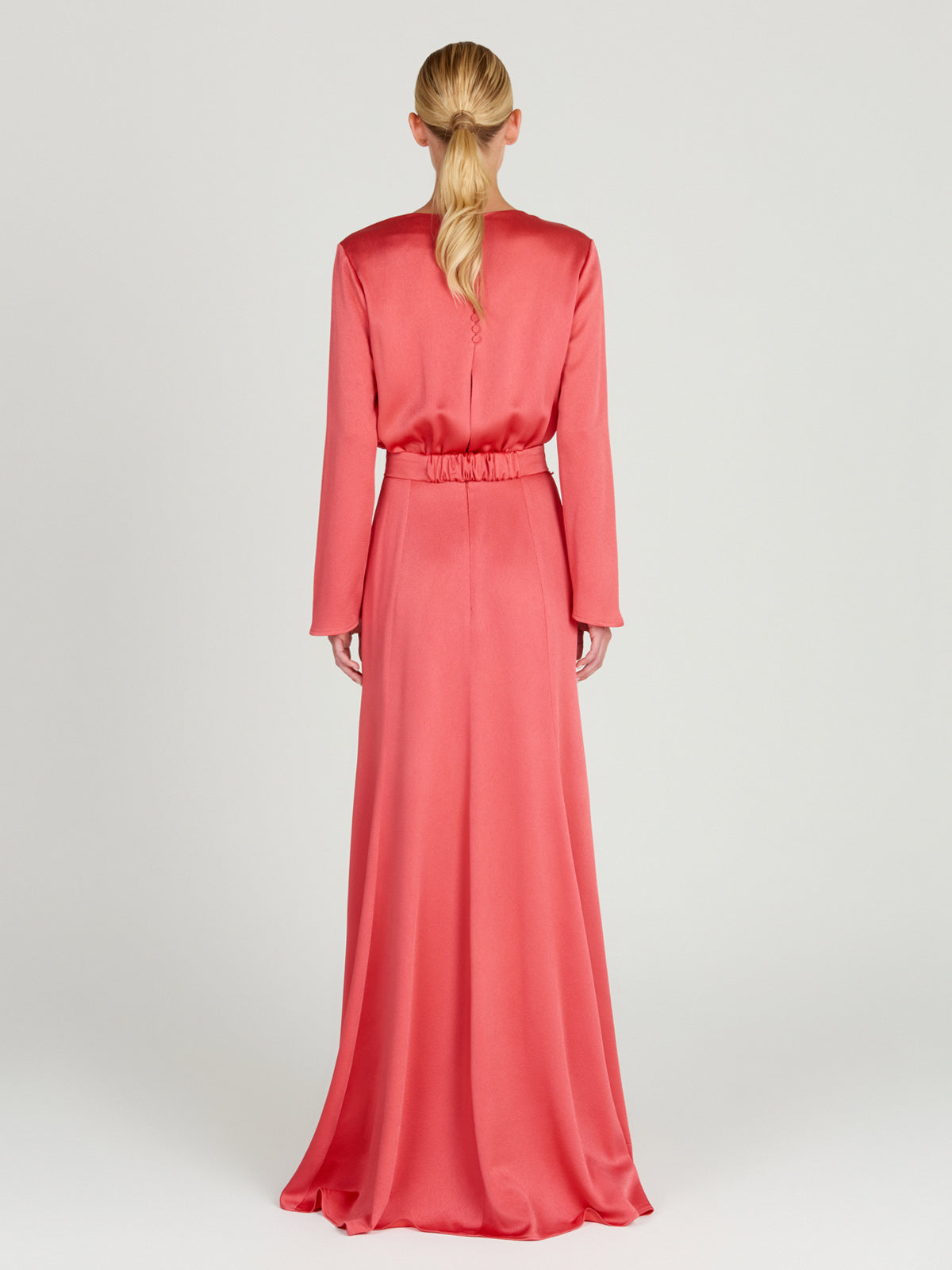 A sleek Ravenna Dress Coral floor-length dress with a belt.