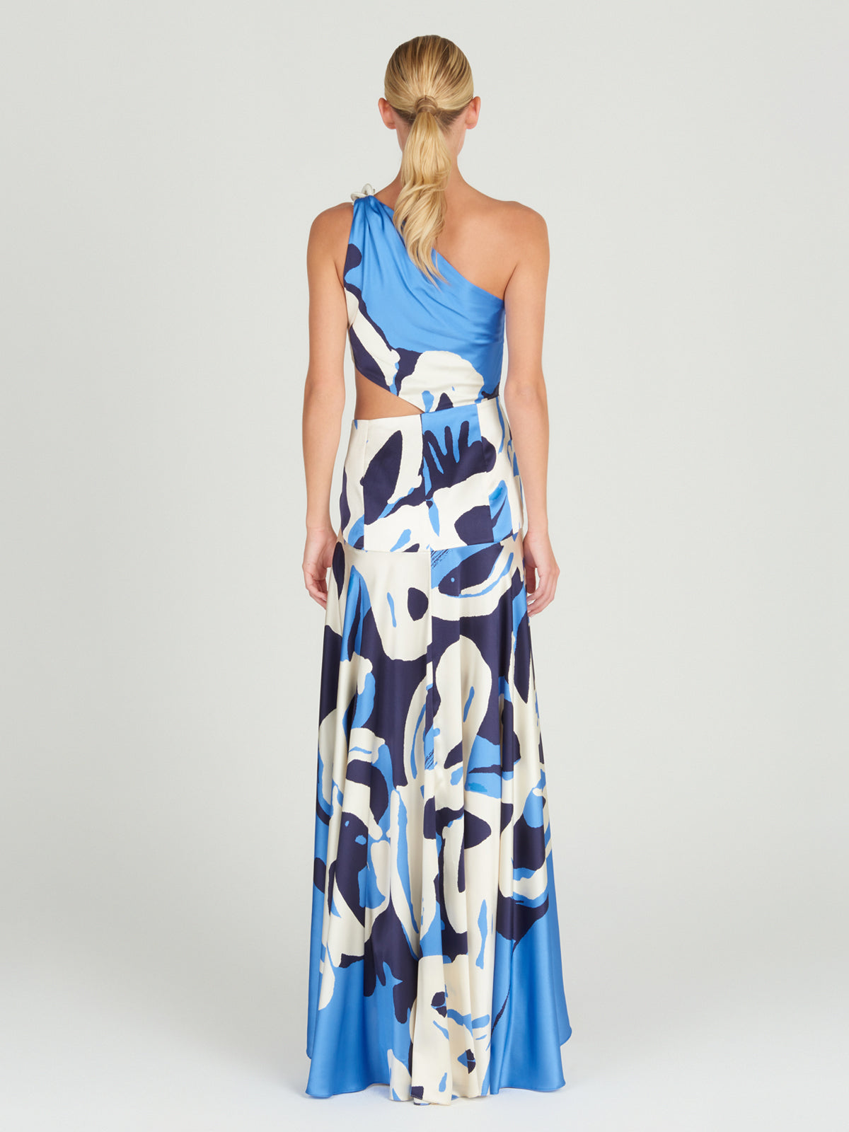 A Whitney Dress Celeste Bloom with an abstract pattern and a one-shoulder silhouette.