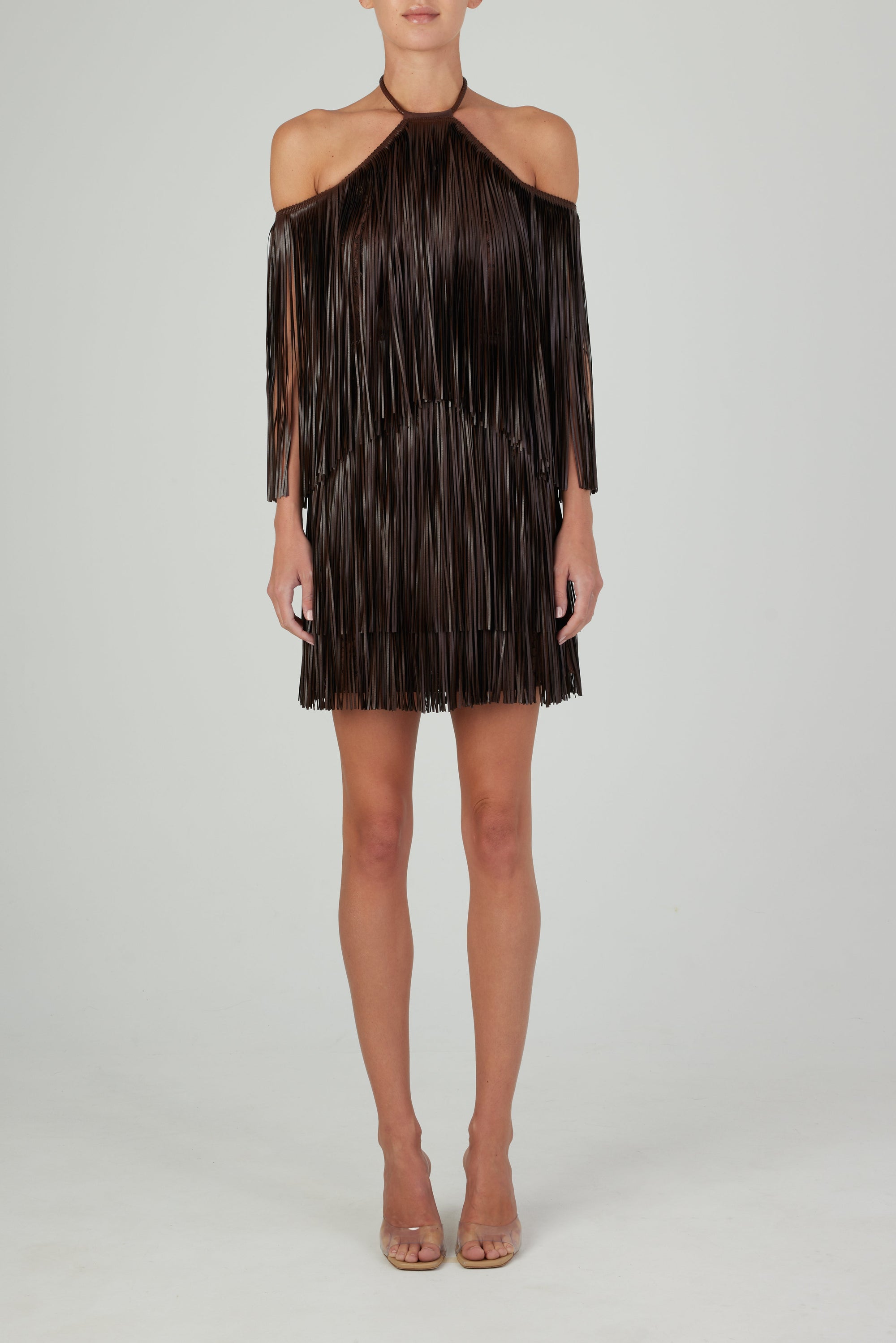The Vercelli Dress Brown, featuring leather-like fringe and a deep chocolate hue, is displayed on a hanger against a plain white background.