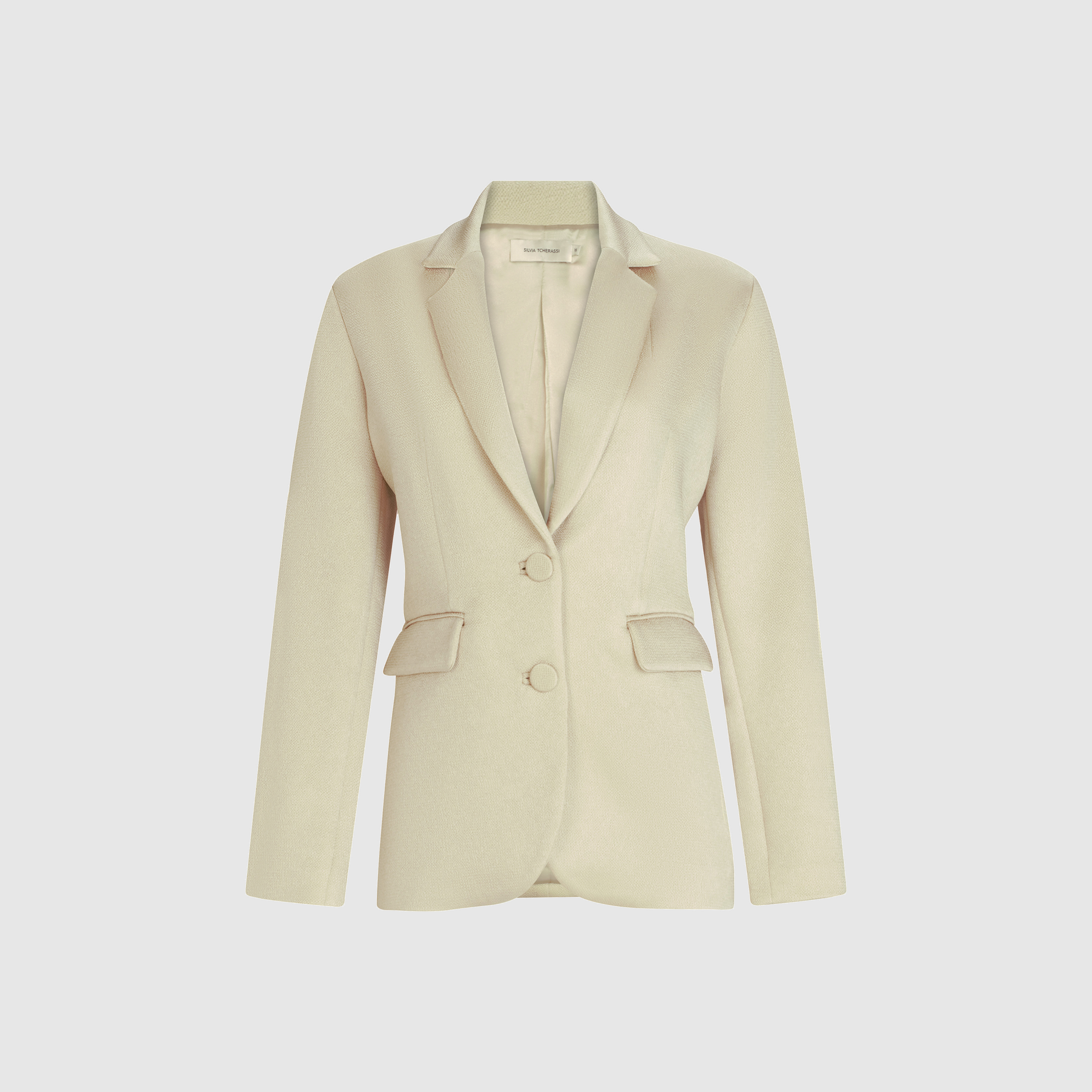 The Rebeca Jacket is a beige women's blazer made from Italian fabric, featuring notched lapels, a structured silhouette, two front buttons, and flap pockets, shown against a plain white background.