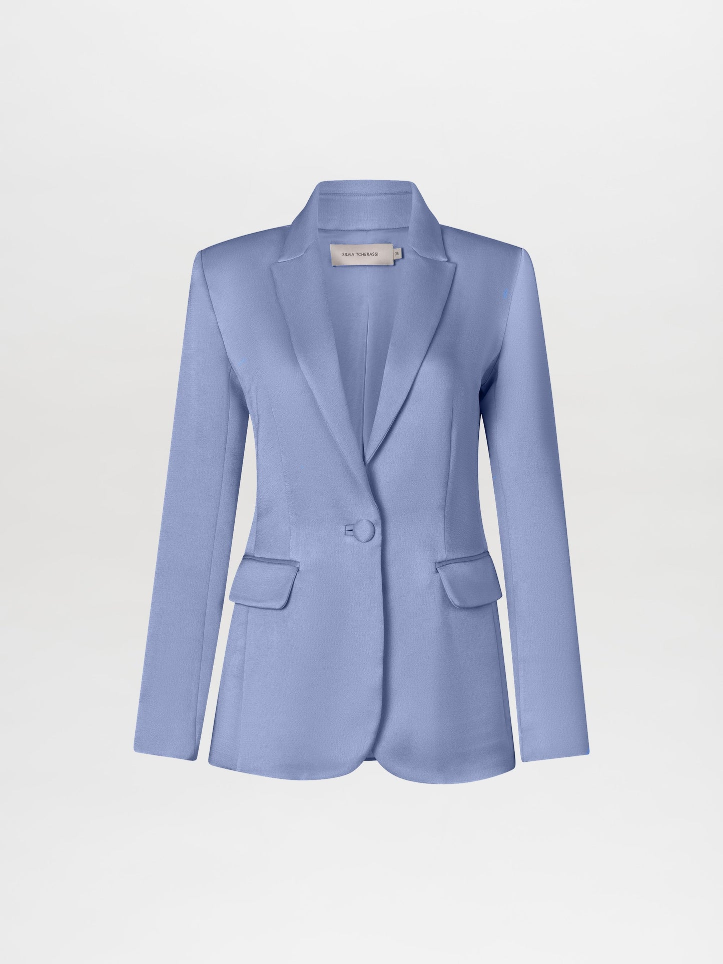 A person wearing the Rebeca Jacket in Periwinkle over a knotted shirt and trousers stands against a plain white background, holding glasses in their right hand. Pre-order now to ensure it arrives by February 15th, 2025!