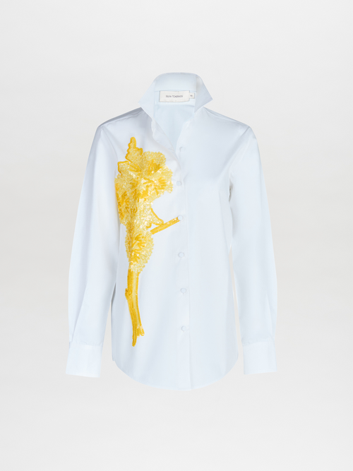 A Rimini Blouse White with a gold embroidered design.