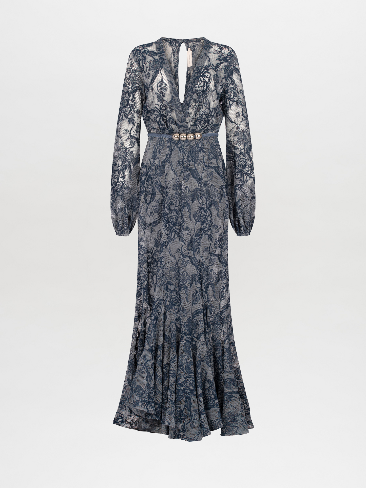 A person in a long, blue lace dress with a deep V-neckline and long sleeves stands against a plain white background, holding a black clutch—the Robin Dress Indigo Lace, available for pre-order, set to ship by November 15th, 2024.