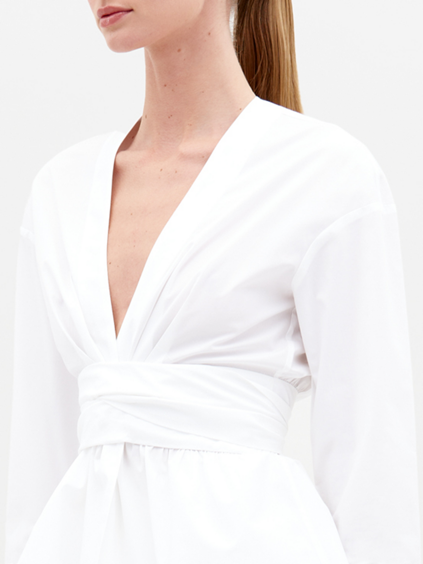 Person wearing the Saanvi Blouse White with lace detail and coordinating white pants, holding a small handbag, looking off to the side against a plain background. Don't miss your chance to pre-order this stunning outfit by the ship-by date of February 15th, 2025.