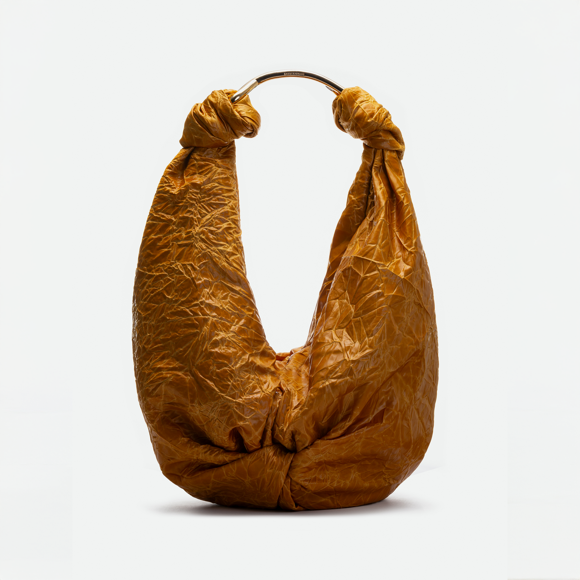 The Sofia Bag Maxi is a brown bag with a crinkled texture, made from Italian fabric. It features a gold circular handle and knotted details on both sides, shown against a plain white background.