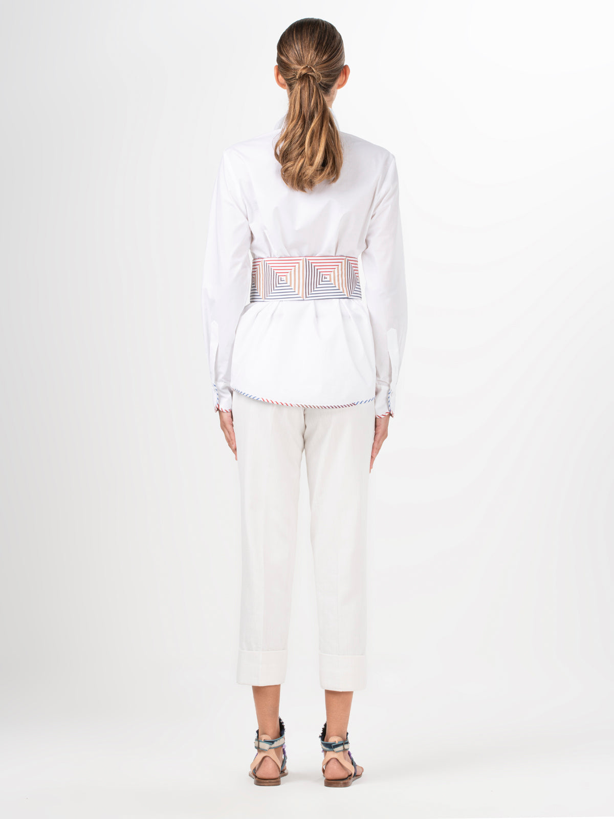 A Berenice Blouse White with a colorful belt and a fitted silhouette.