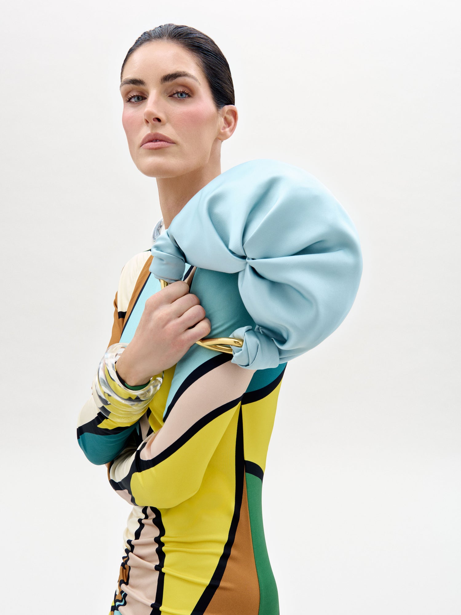 Woman wearing a colorful outfit with a light blue jacket and patterned dress on a white background