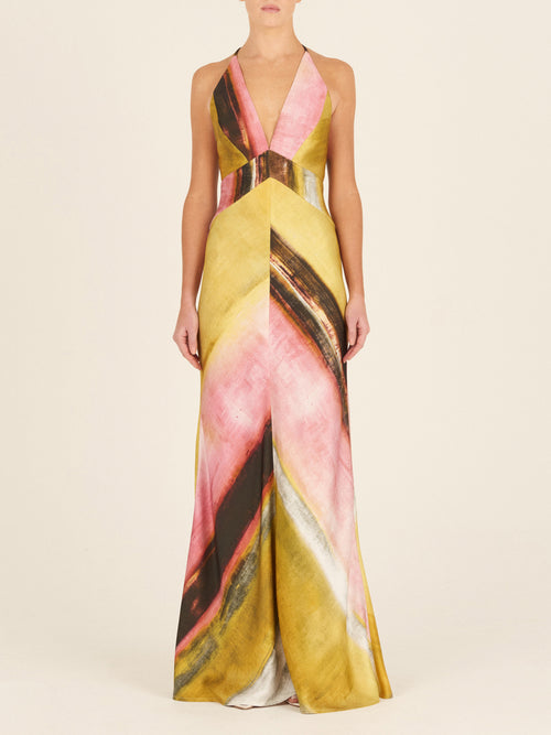 The Daniela Dress Canary Pink Stripes is a sleeveless, full-length piece crafted from crepe de silk, featuring a multicolor abstract pattern with canary pink stripes, a v-neckline, and crisscross straps at the back.