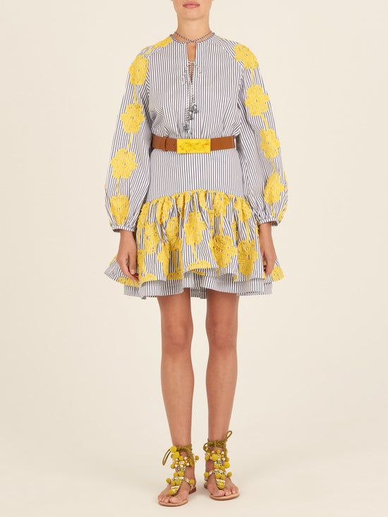 The Molveno Blouse Yellow Embroidered Flowers is a blue and white striped blouse adorned with yellow floral embroidery on the sleeves and shoulders, featuring a tied neckline and long, gathered sleeves. This piece exemplifies high fashion with its intricate details and elegant design.