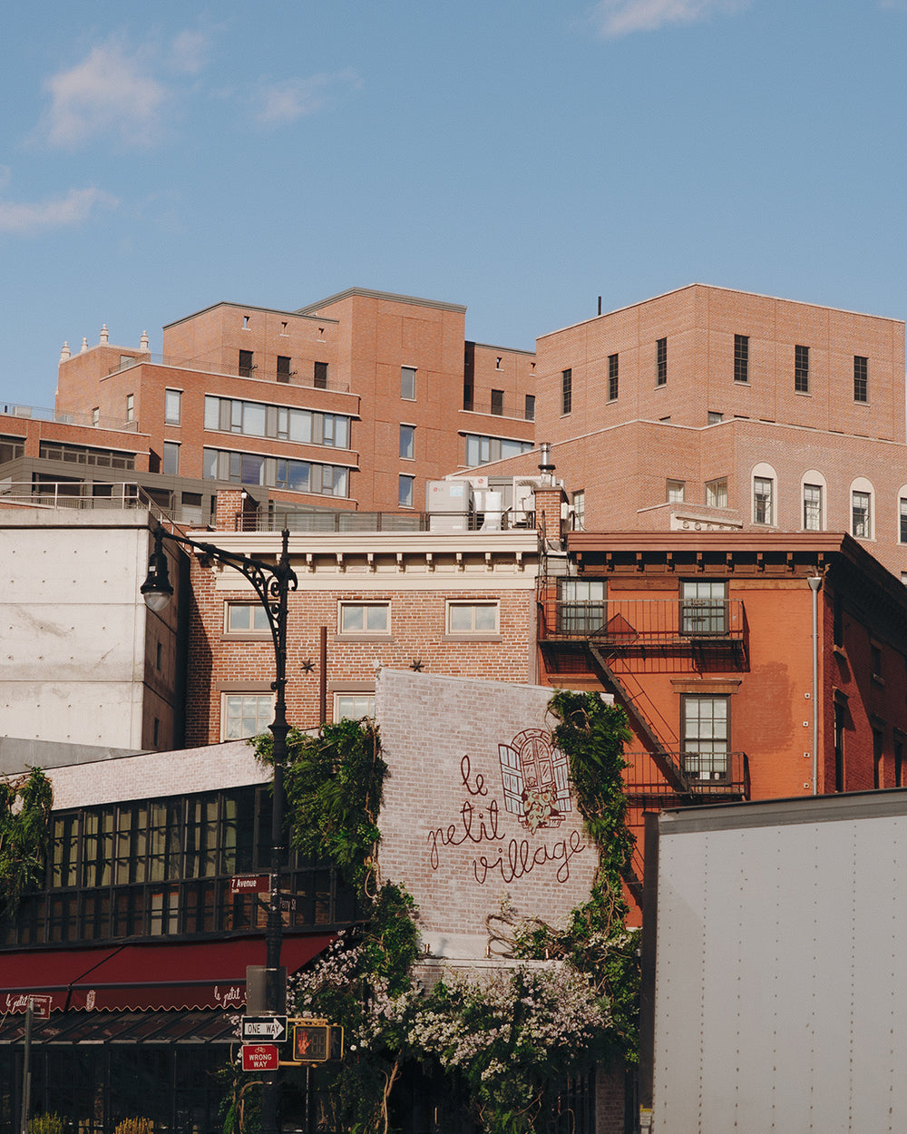 Brick buildings with a sign reading 'Le petit village' against a blue sky.