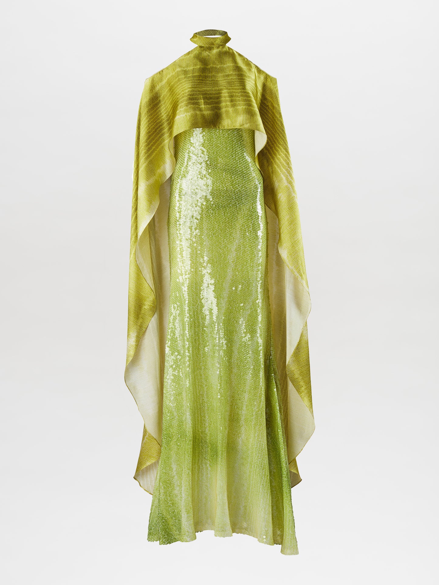 A woman stands wearing the Adelia Dress Green Moire, a long, flowing lime-green gown with off-the-shoulder sleeves and a high neckline. Set against a plain, light-colored background, this stunning dress is available for pre-order now to ensure it reaches you by the ship-by date of February 1st, 2025.