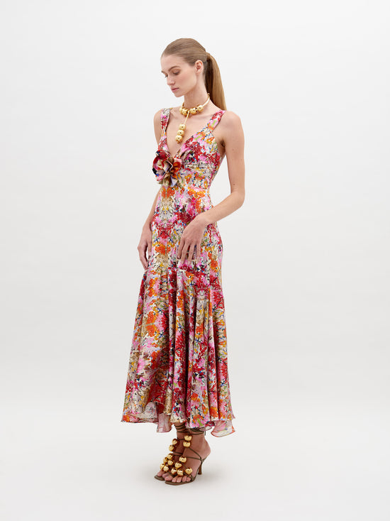 A woman in a Saskya Dress Multicolor Animal Print with a fitted bodice and flared skirt stands with her back to the camera, showcasing her outfit and wearing heeled sandals. Be sure to pre-order now for guaranteed delivery by the ship-by date of November 15th, 2024.