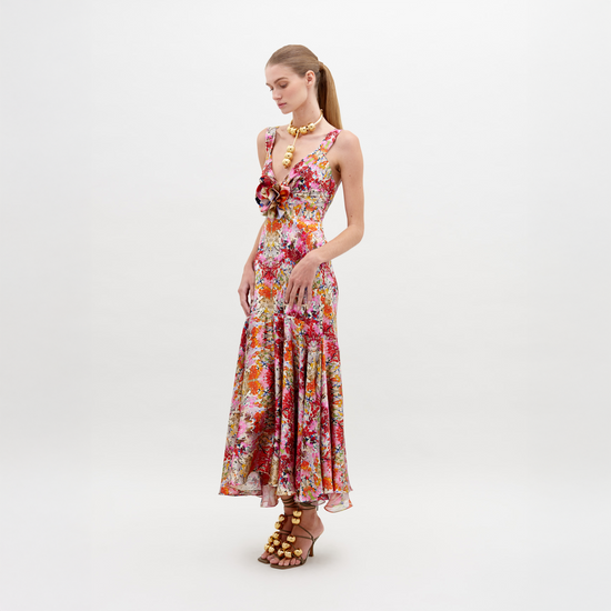 A woman in a Saskya Dress Multicolor Animal Print with a fitted bodice and flared skirt stands with her back to the camera, showcasing her outfit and wearing heeled sandals. Be sure to pre-order now for guaranteed delivery by the ship-by date of November 15th, 2024.