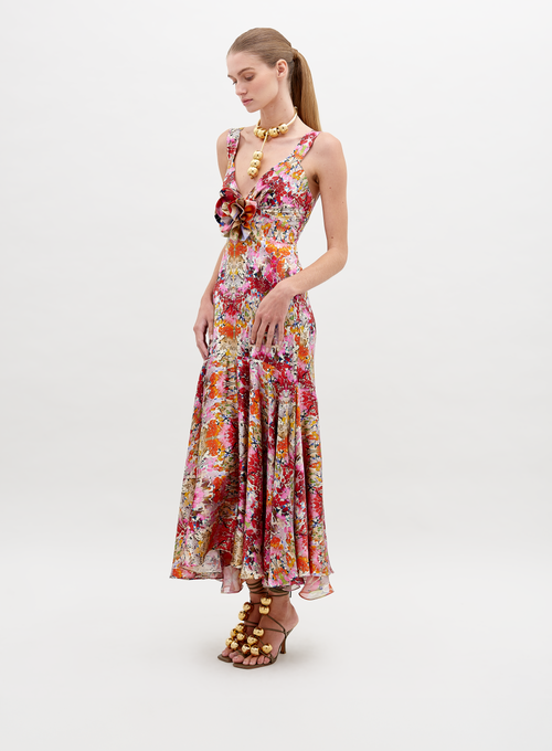 A woman in a Saskya Dress Multicolor Animal Print with a fitted bodice and flared skirt stands with her back to the camera, showcasing her outfit and wearing heeled sandals. Be sure to pre-order now for guaranteed delivery by the ship-by date of November 15th, 2024.